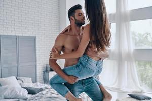 casal feliz em casa. lindo casal jovem abraçando em pé no quarto foto