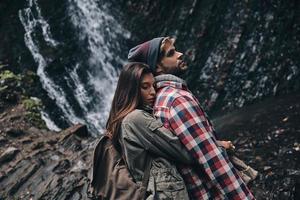 nada mais que amor. lindo casal jovem abraçando em pé perto da cachoeira foto
