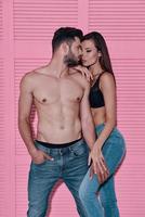 casal perfeito. lindo casal jovem abraçando em pé contra um fundo rosa foto