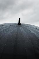 uma imagem de chuva batendo em um guarda-chuva preto