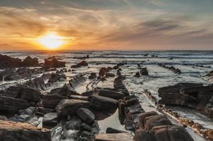 Praia Barrika ao pôr do sol. longa exposição na costa rochosa foto