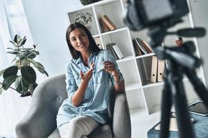 truques de beleza. mulher jovem e atraente mostrando produto de beleza ao fazer novo vídeo dentro de casa foto