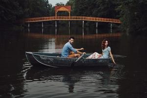 feliz por estar apaixonado. lindo casal jovem sorrindo enquanto desfruta de um encontro romântico no lago foto