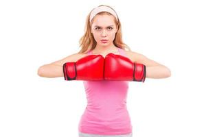 pronto para lutar. mulher de cabelo loiro concentrado na camisa rosa e luvas de boxe, olhando para a câmera em pé isolado no fundo branco foto