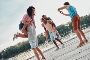 capturando momentos felizes. belos casais jovens passando tempo despreocupado em pé no cais foto