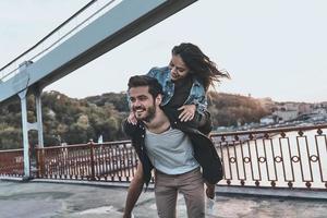 curtindo cada momento juntos. jovem casal se divertindo ao ar livre enquanto homem bonito dando carona para sua namorada foto