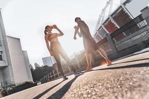 dando um tempo. comprimento total do jovem casal em roupas esportivas, fazendo uma pausa para beber água enquanto se exercita ao ar livre foto