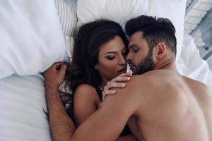 cada vez mais quente. vista superior do lindo casal jovem fazendo amor enquanto estava deitado na cama foto