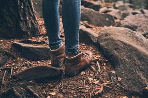 usando botas confortáveis. close-up da mulher moderna em pé na floresta enquanto desfruta de sua viagem nas montanhas foto