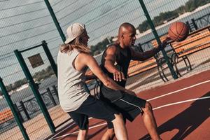pronto para superar qualquer obstáculo. dois jovens em roupas esportivas jogando basquete enquanto passam tempo ao ar livre foto