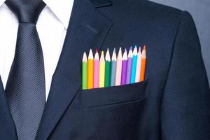 empresário multicolorido. close-up de um bolso de empresário com lápis coloridos em pé contra o quadro-negro foto