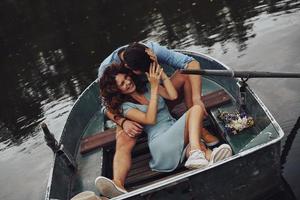 totalmente feliz. vista superior lindo casal jovem abraçando e sorrindo enquanto desfruta de um encontro romântico no lago foto