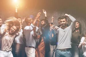 hora da festa. grupo de jovens bonitos dançando juntos e parecendo felizes foto