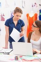 resolvendo os problemas do dia a dia. duas belas designers femininas discutindo algo enquanto olham para o laptop foto