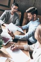 inspirado a trabalhar duro. vista superior de jovens modernos em roupas casuais inteligentes discutindo negócios enquanto está sentado no escritório criativo foto