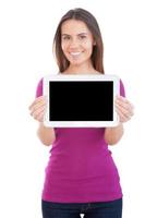 copie o espaço em seu tablet digital. jovem alegre mostrando seu tablet digital e sorrindo em pé isolado no branco foto