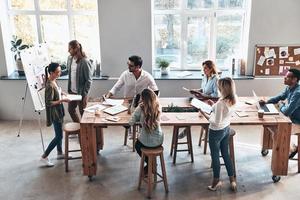 planejamento de novas estratégias de negócios. vista superior de dois jovens colegas modernos realizando uma apresentação de negócios em pé na sala de reuniões foto