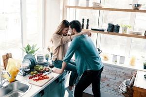 amando mais que tudo. vista superior do belo casal jovem união cara a cara em pé na cozinha em casa foto