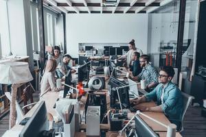 rotina de negócios. grupo de jovens empresários concentrando-se em seu trabalho enquanto estão sentados na grande mesa de escritório juntos foto