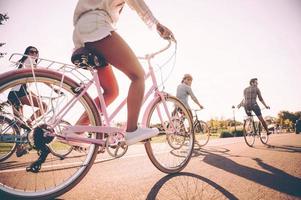 passeio despreocupado. vista de ângulo baixo de jovens alegres andando de bicicleta ao longo de uma estrada juntos foto