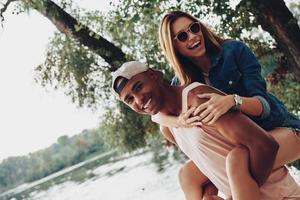 sentindo-se livre para fazer qualquer coisa. casal jovem feliz sorrindo em pé perto do lago foto