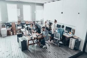 concentrado no trabalho. vista superior de jovens modernos em roupas casuais, concentrando-se em seus projetos enquanto trabalham juntos atrás da parede de vidro no escritório criativo foto