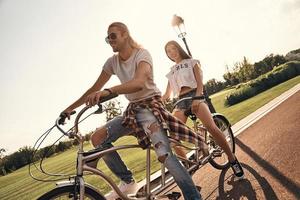 o amor os inspira. lindo casal jovem em roupas casuais andando de bicicleta juntos enquanto passa um tempo despreocupado ao ar livre foto