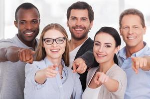 nós escolhemos seu grupo de empresários alegres em roupas casuais próximos uns dos outros e apontando para você foto