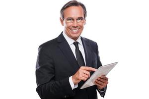 empresário com tablet digital. homem maduro confiante em trajes formais trabalhando em tablet digital e sorrindo em pé isolado no fundo branco foto