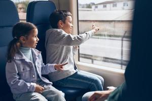 duas crianças felizes curtindo a viagem de trem com a família foto