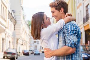 o amor está no ar. lindo jovem casal apaixonado abraçando e olhando um ao outro em pé ao ar livre foto