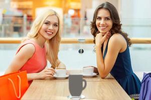 relaxando depois das compras. duas belas mulheres tomando café no restaurante e olhando para a câmera foto