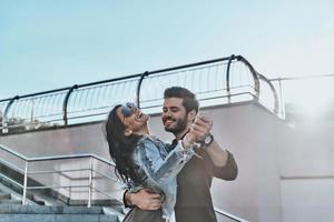 dança espontânea. lindo casal jovem dançando e sorrindo enquanto passa o tempo ao ar livre foto