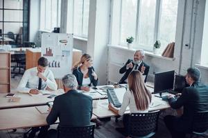 vista superior dos colegas de trabalho discutindo a próxima etapa do negócio enquanto trabalha em conjunto com colegas no escritório moderno foto