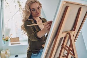mulher jovem e atraente de cabelo loiro pintando no estúdio de arte foto