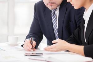 trabalho em equipe. imagem recortada de dois empresários confiantes discutindo algo enquanto estão sentados juntos à mesa foto