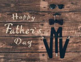 Dia dos Pais. tiro de alto ângulo de suspensórios, adereço, gravata borboleta e óculos deitado na mesa de madeira foto