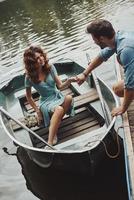 afogando-se em seus olhos. feliz casal jovem se preparando para remar um barco enquanto desfruta de seu encontro ao ar livre foto