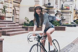 eu amo minha bicicleta bela jovem andando de bicicleta ao longo da rua e sorrindo foto