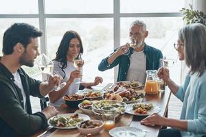 família moderna de várias gerações bebendo vinho enquanto jantam juntos foto