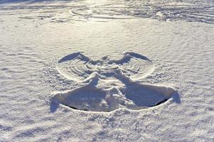 impressão de um anjo de neve na neve branca fresca e abstrato do lago congelado, diversão de inverno foto