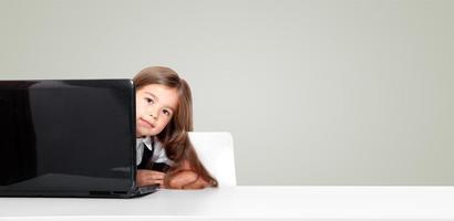 menina da escola adolescente feliz e fofa sentada no laptop foto