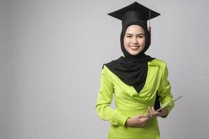 jovem mulher muçulmana sorridente com hijab usando chapéu de formatura, educação e conceito universitário foto