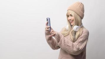 retrato de uma jovem caucasiana vestindo suéter segurando o telefone inteligente sobre fundo branco foto