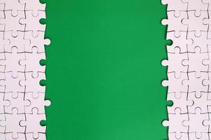 fragmento de um quebra-cabeça branco dobrado no fundo de uma superfície de plástico verde. foto de textura com espaço de cópia para texto