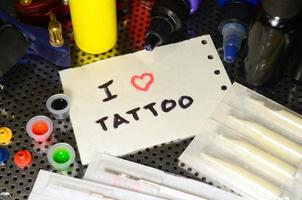 eu amo tatuagem. o texto está escrito em uma pequena folha de papel entre vários equipamentos para tatuagem foto