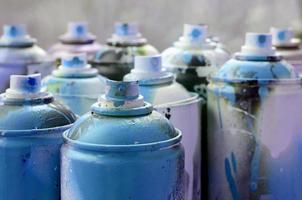 muitas latas de aerossol sujas e usadas de tinta azul brilhante. fotografia macro com profundidade de campo rasa. foco seletivo no bico de pulverização foto