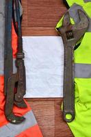 chaves ajustáveis e mentiras de papel de camisas de um trabalhador de sinal laranja e verde foto