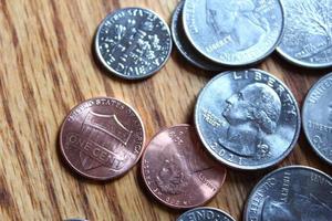 moedas de dólar e notas de dólar espalhadas em uma mesa de madeira, moedas de dólar planas leigas. foto
