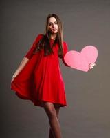 mulher de vestido vermelho segurando o símbolo do coração